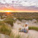 Frau sitzt beim Sonnenuntergang in einer Dünenlandschaft auf Texek