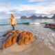 Frau steht am Meer auf einem Felsen
